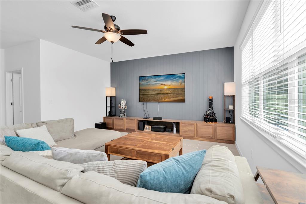 A living room features a gray accent wall, a wall-mounted television, and a sectional sofa — 4199 BIG SKY DRIVE, SPRING HILL, FL