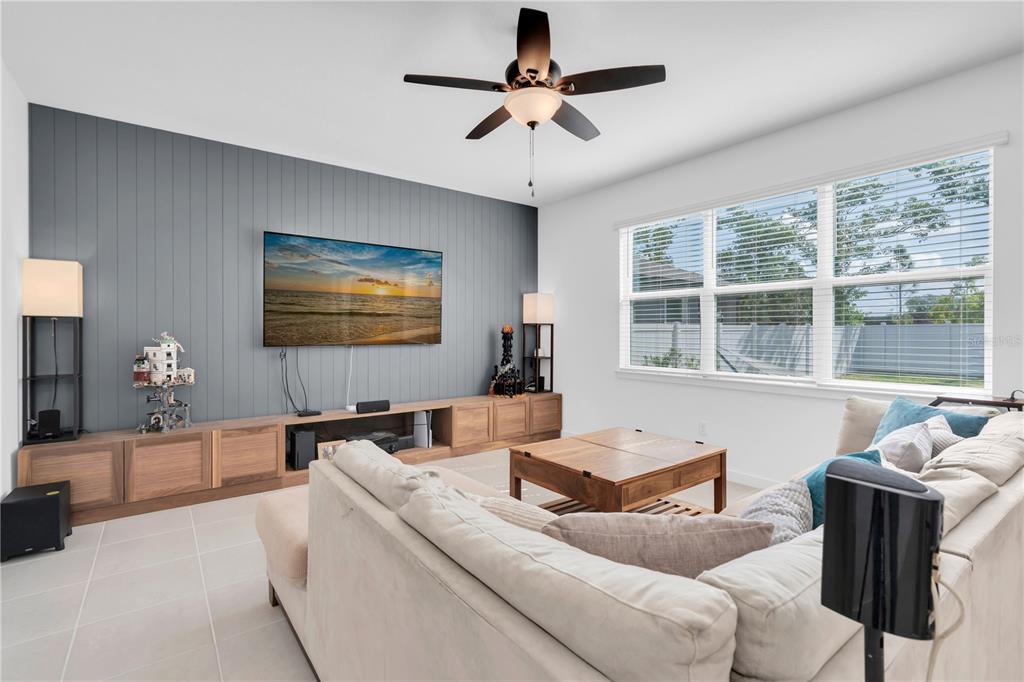 A living room features a gray shiplap accent wall, a large media console, and a sectional — 4199 BIG SKY DRIVE, SPRING HILL, FL
