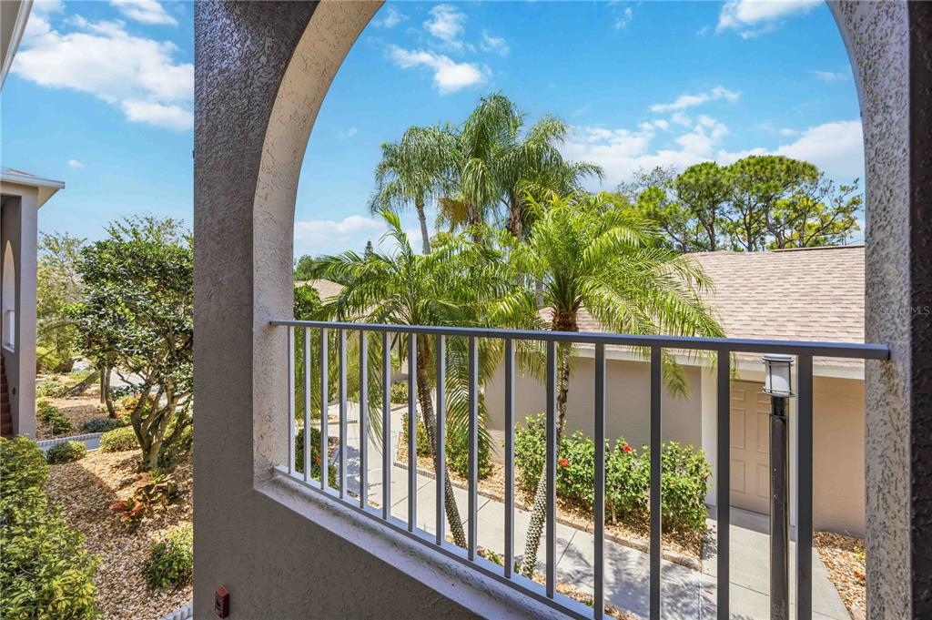 A view from an arched balcony overlooking a walkway, palm trees, and neighboring buildings — 8951 VERANDA WAY UNIT 623, SARASOTA, FL