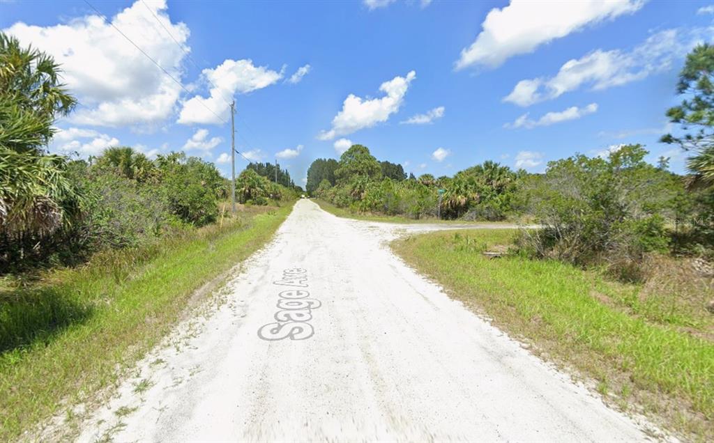 A dirt road stretches through a rural, undeveloped area with dense vegetation and blue skies — 2954 SAGE AVENUE SW, PALM BAY, FL