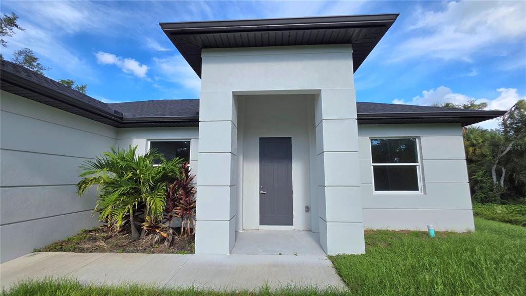 A modern single-story house exterior features a gray front door under a prominent entryway tower — 286 KRIEGER STREET, PORT CHARLOTTE, FL