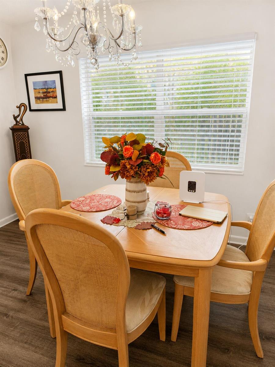 A dining room features a wooden table with four chairs, a floral centerpiece, and a chandelier — 415 Normandy Lane # I, Delray Beach FL 33484, DELRAY BEACH, FL
