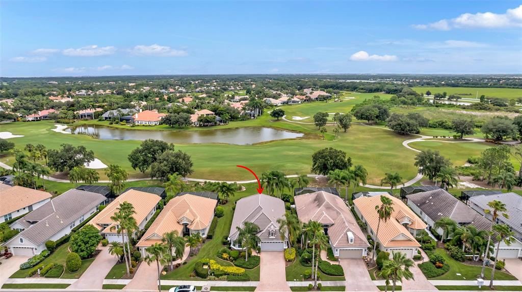 An aerial view shows a row of suburban houses overlooking a golf course and lake — 7163 SANDHILLS PLACE, LAKEWOOD RANCH, FL