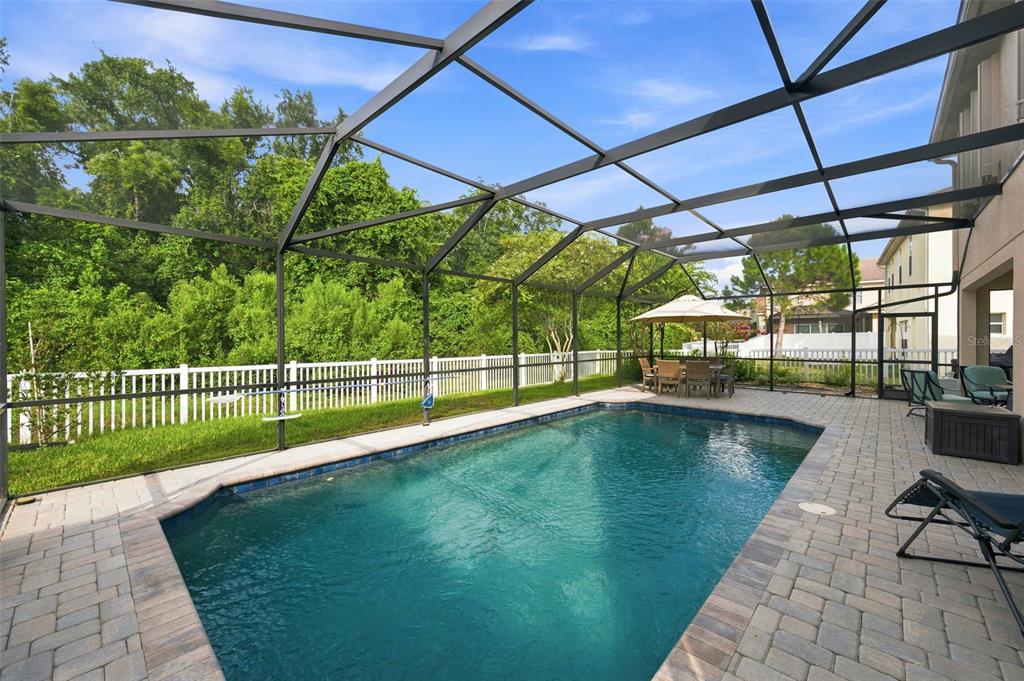 A swimming pool with a paver deck is enclosed by a screened lanai — 11507 BELLE HAVEN DRIVE, NEW PORT RICHEY, FL