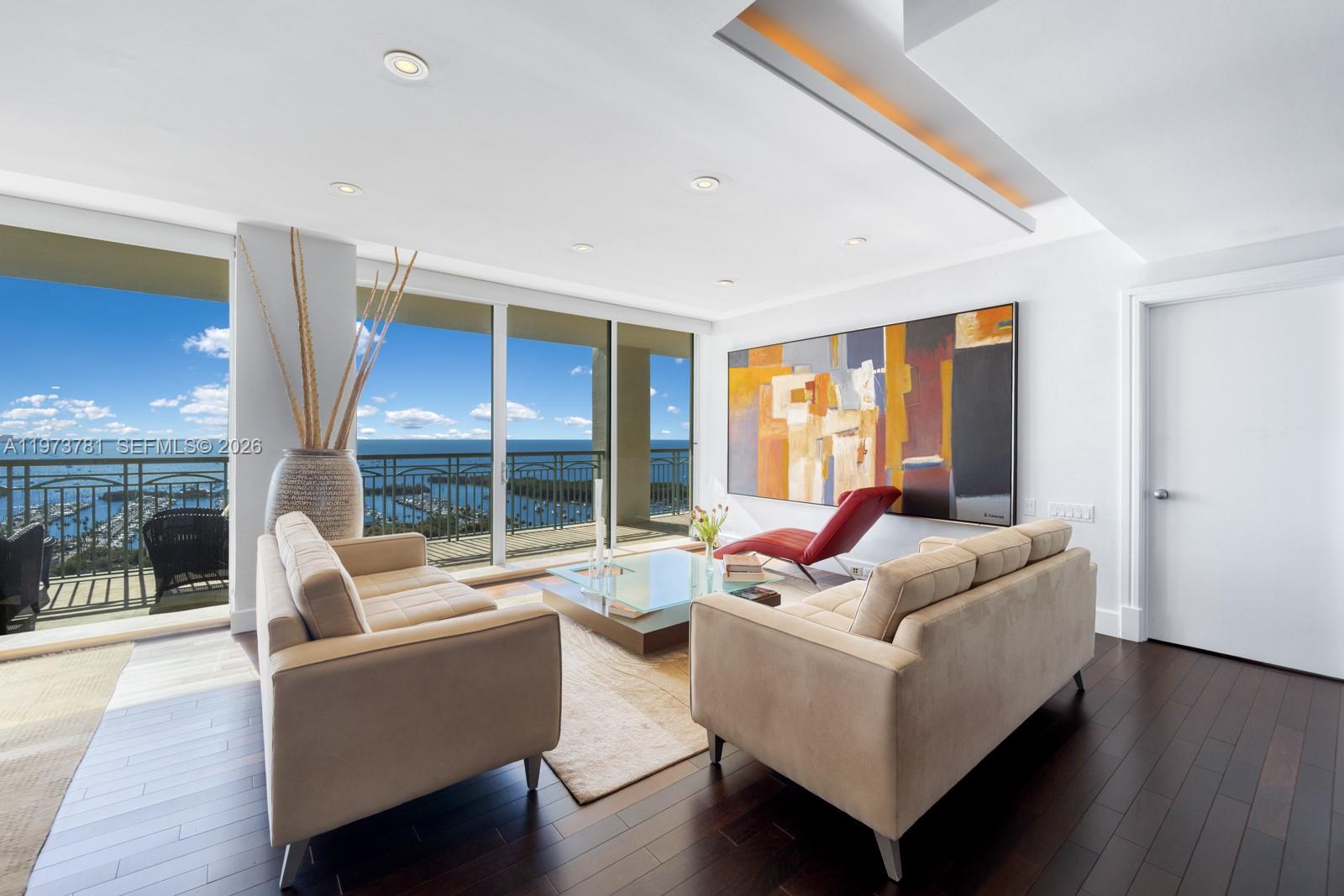 A modern living room features two beige sofas, a glass coffee table, and ocean views — 3400 SW 27th Ave # 2102, Miami FL 33133, MIAMI, FL