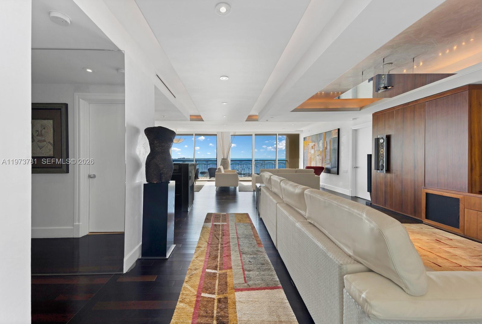 A modern living room features a white sectional sofa, dark wood floors, and ocean views — 3400 SW 27th Ave # 2102, Miami FL 33133, MIAMI, FL
