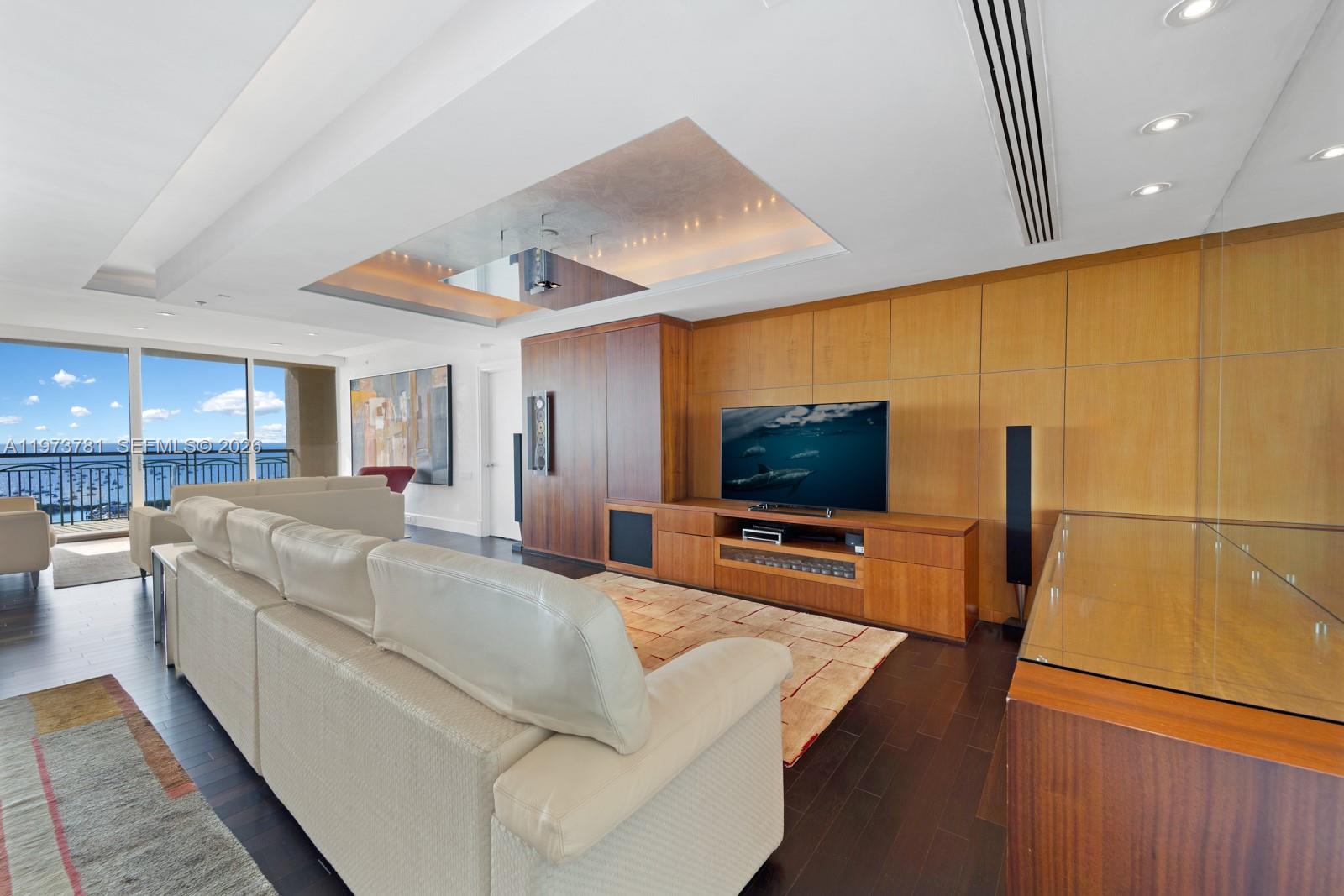 A living room features a white sofa, wood paneling, a television, and a balcony view — 3400 SW 27th Ave # 2102, Miami FL 33133, MIAMI, FL