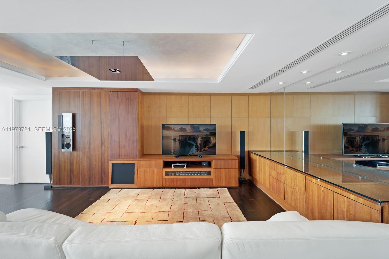 A living room features wood-paneled walls, a media console, a television, and a white sofa — 3400 SW 27th Ave # 2102, Miami FL 33133, MIAMI, FL