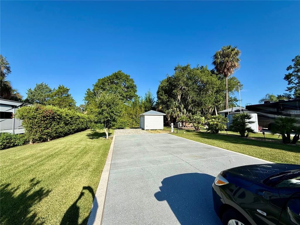 A paved driveway leads to a small shed on a grassy lot with trees — 3054 NE 101ST TERRACE UNIT 127, SILVER SPRINGS, FL