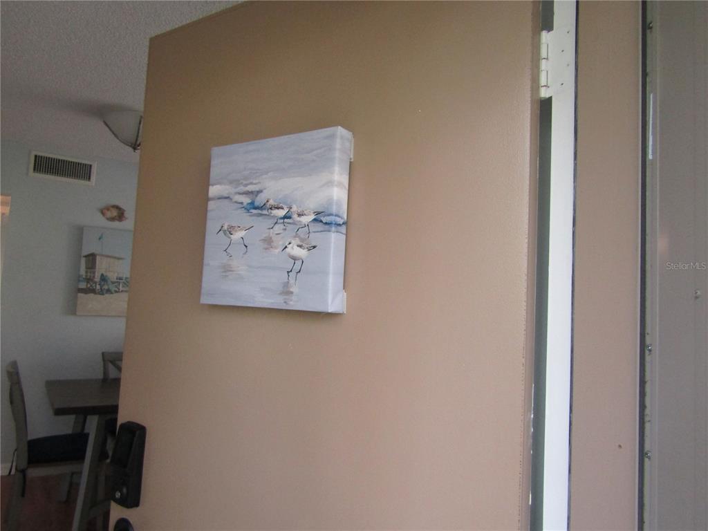 A square canvas painting of shorebirds hangs on a tan wall near a doorway — 5136 HARPERS CROFT UNIT 11, SARASOTA, FL