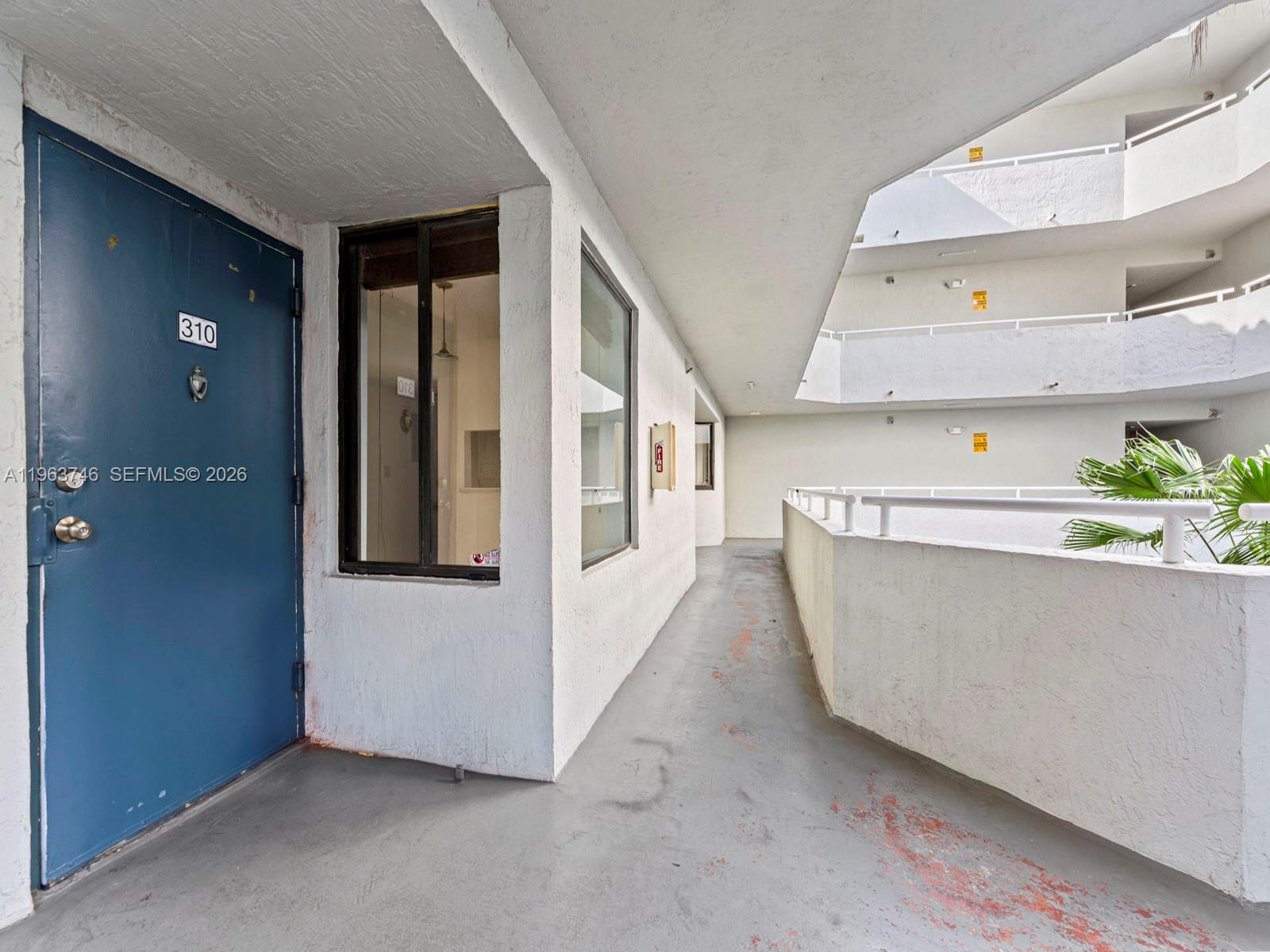An exterior walkway leads to a blue door marked 310 in a multi-story apartment complex — 8365 SW 152nd Ave # 310, Miami FL 33193, MIAMI, FL