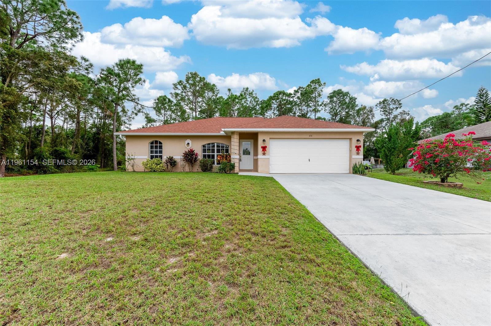 A single-story house with a tan stucco exterior, a red roof, and a concrete driveway — 436 BROADMOOR ST, Lehigh Acres FL 33974, LEHIGH ACRES, FL