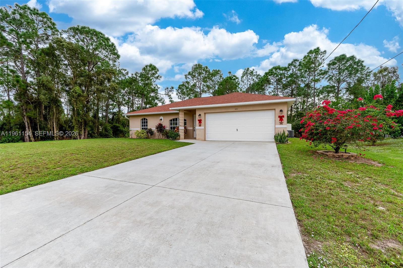A single-story house with a white garage door, tan stucco exterior, and a red roof — 436 BROADMOOR ST, Lehigh Acres FL 33974, LEHIGH ACRES, FL