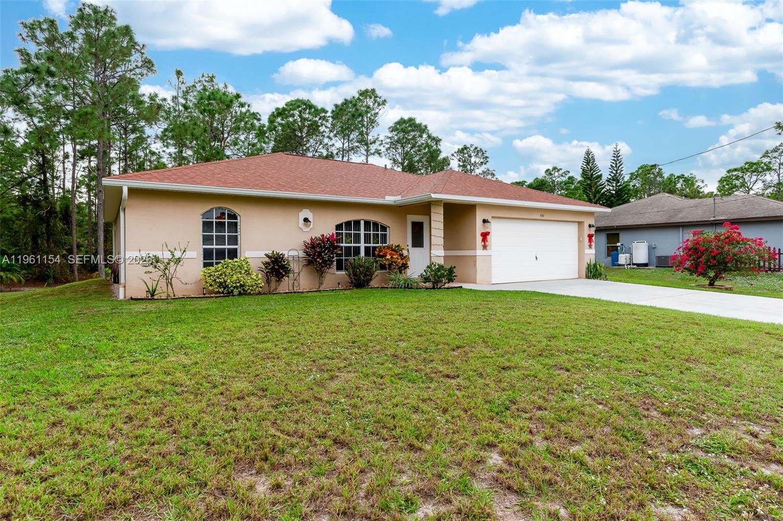 A single-story house with a tan stucco exterior, a red roof, and a two-car garage — 436 BROADMOOR ST, Lehigh Acres FL 33974, LEHIGH ACRES, FL