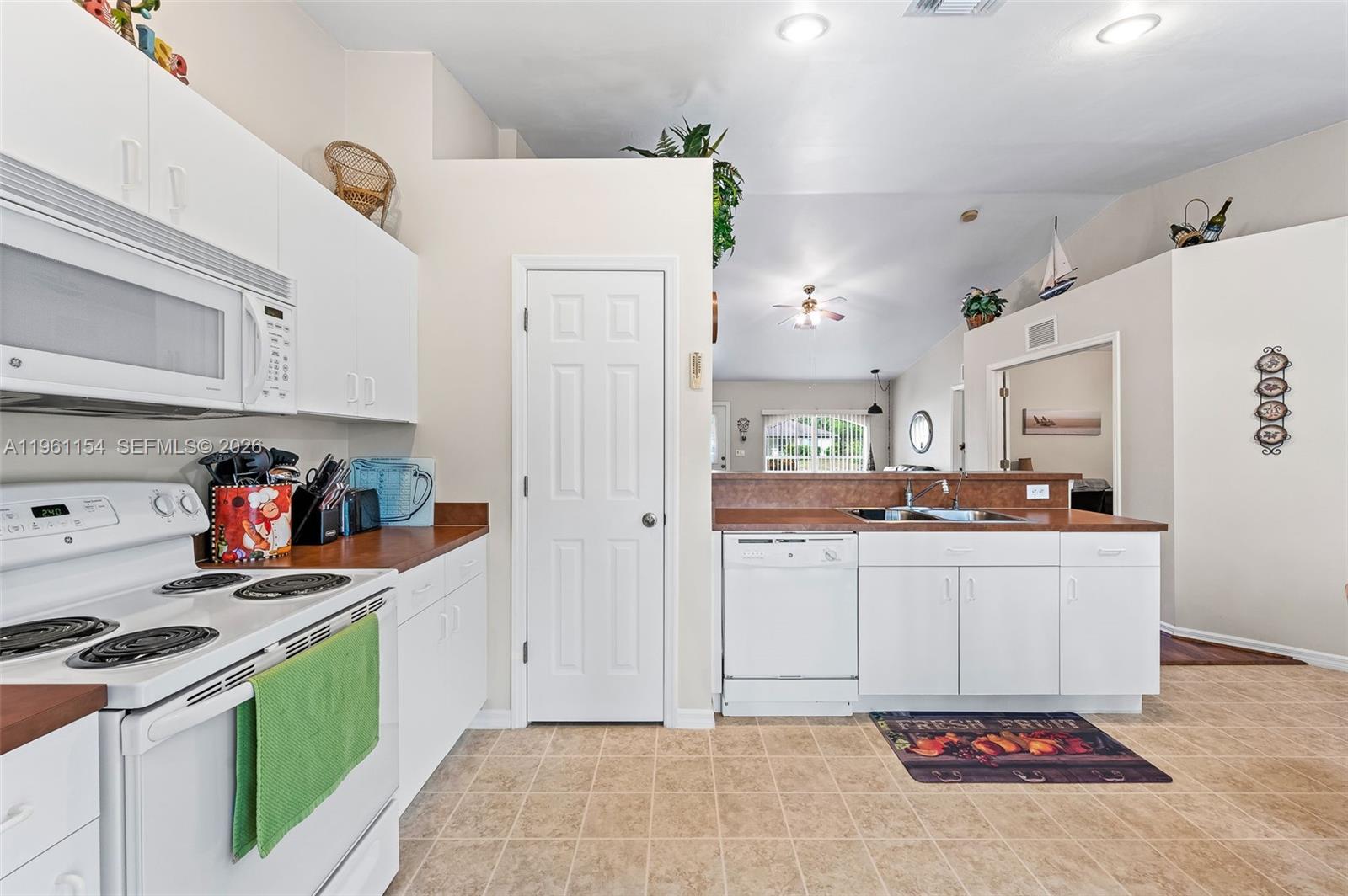 A kitchen features white cabinets, a white stove, a dishwasher, and tan tile flooring — 436 BROADMOOR ST, Lehigh Acres FL 33974, LEHIGH ACRES, FL