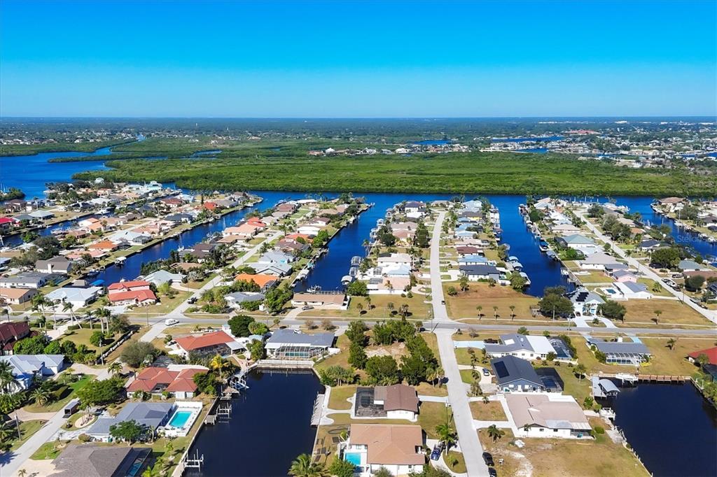An aerial view shows a residential neighborhood with houses situated along multiple canals — 4358 HARBOR BOULEVARD, PORT CHARLOTTE, FL