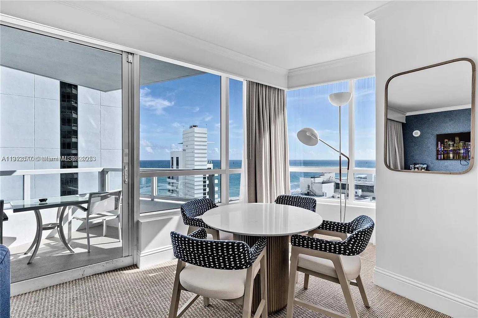 A dining area with a round table, patterned chairs, and floor-to-ceiling windows overlooking the ocean — 4401 Collins Ave # 1604, Miami Beach FL 33140, MIAMI BEACH, FL