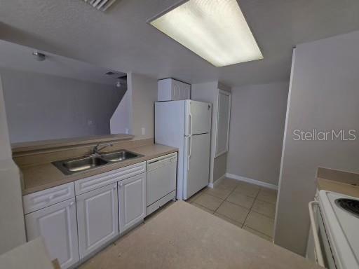 A kitchen features white cabinets, a double sink, a white refrigerator, and tiled flooring — 2419 FAN PALM DRIVE, DAVENPORT, FL