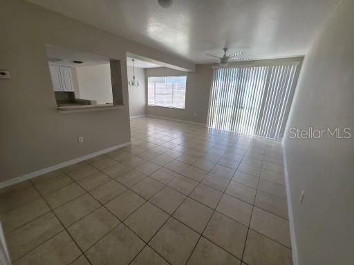 An open-concept living and dining area features light-colored tile flooring and a sliding glass door — 2419 FAN PALM DRIVE, DAVENPORT, FL
