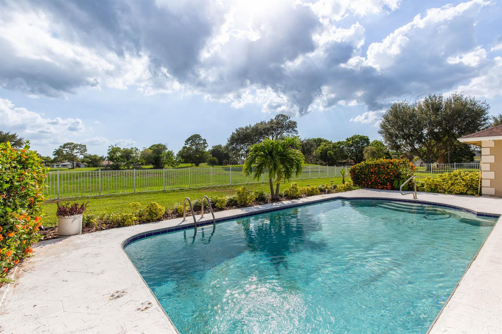 A swimming pool with a metal ladder sits on a patio overlooking a fenced yard — 1327 Pine Valley Drive, Wellington FL 33414, WELLINGTON, FL
