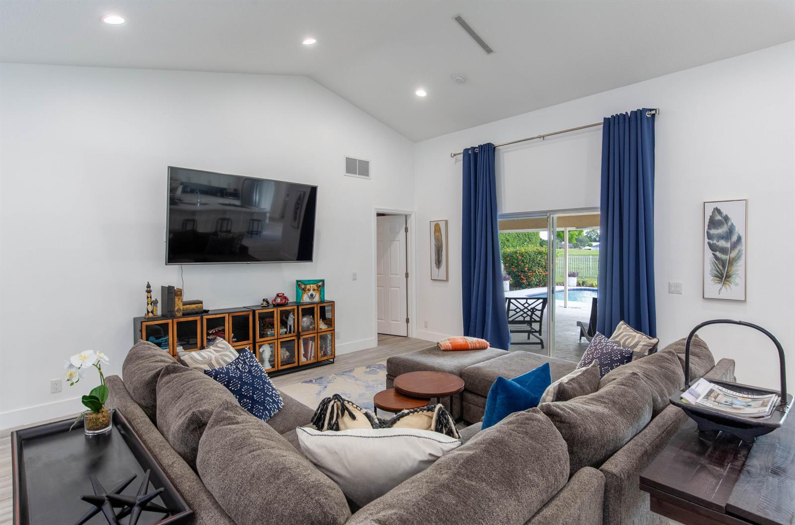 A living room features a large sectional sofa, a wall-mounted television, and sliding glass doors — 1327 Pine Valley Drive, Wellington FL 33414, WELLINGTON, FL