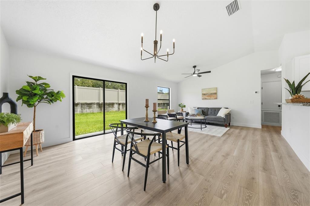 A bright open-concept living and dining area features light wood floors and a modern chandelier — 350 LAKE CRESCENT DRIVE, DEBARY, FL
