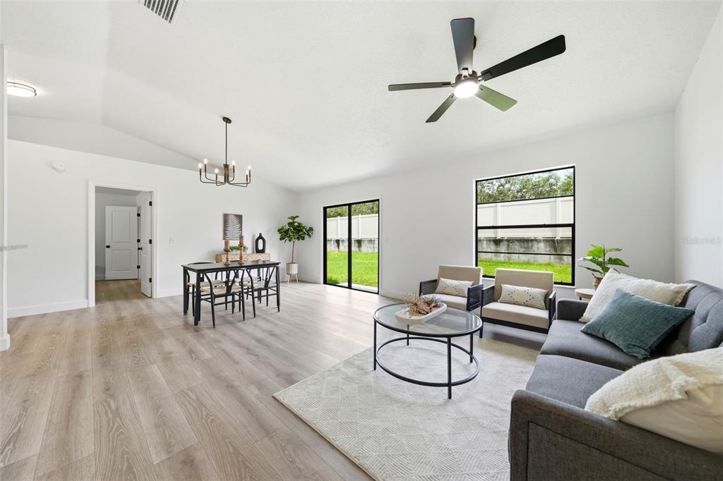 A bright living and dining area with light wood floors, white walls, and a ceiling fan — 350 LAKE CRESCENT DRIVE, DEBARY, FL
