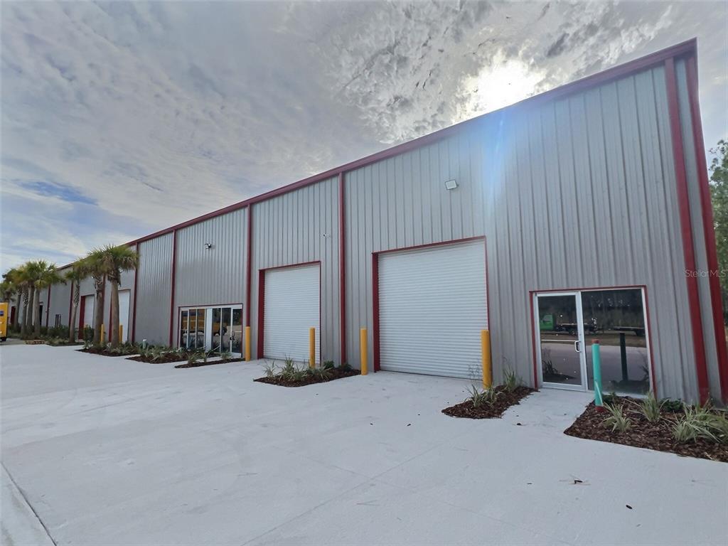 A modern industrial warehouse building features metal siding, roll-up doors, and glass entryways — 25 RAILSIDE WAY UNIT B, PALM COAST, FL