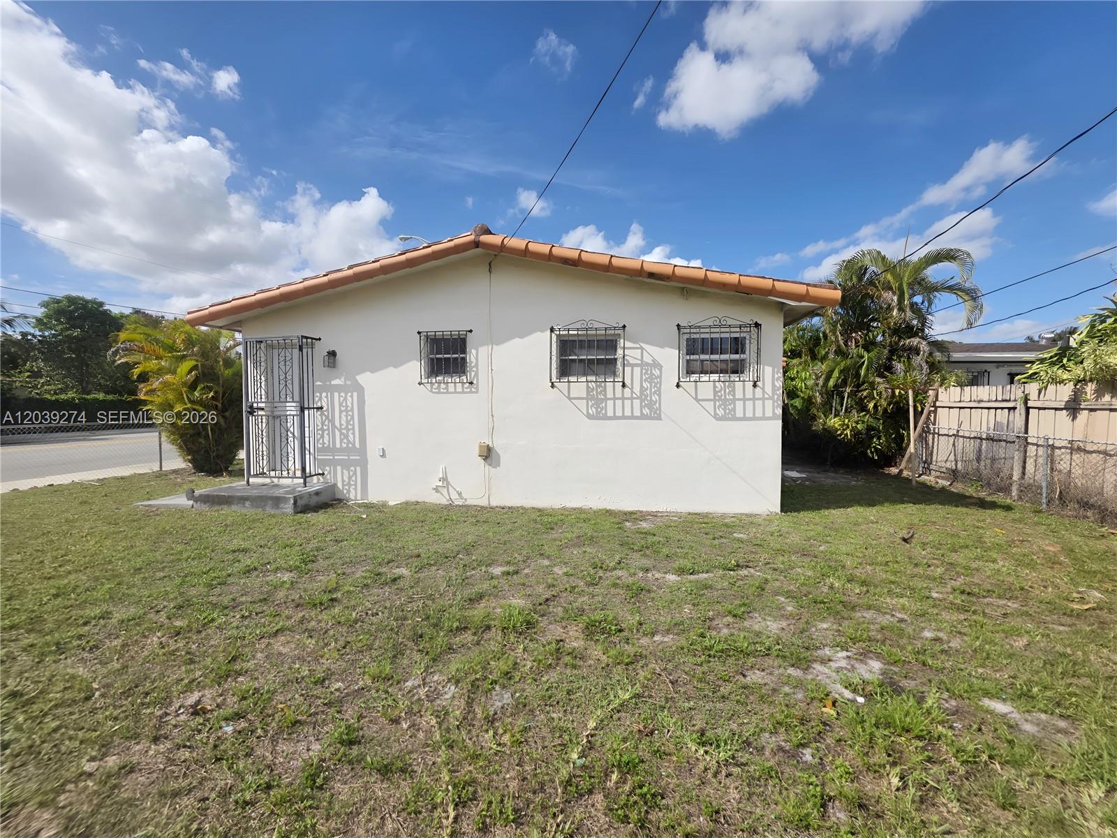 A single-story house with a white stucco exterior, tile roof, and metal window security bars — 405 SE 4th Ave, Hialeah FL 33010, HIALEAH, FL