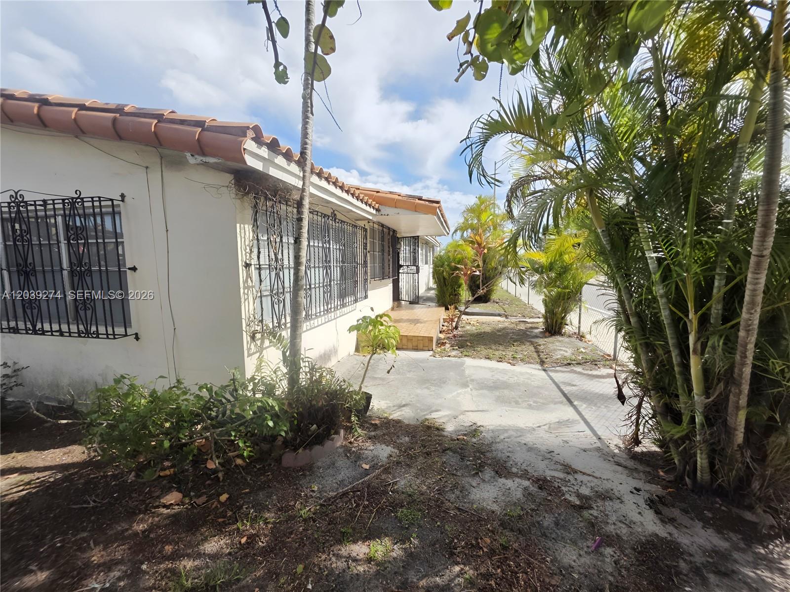 The exterior of a house features a tiled roof, security bars on windows, and landscaping — 405 SE 4th Ave, Hialeah FL 33010, HIALEAH, FL