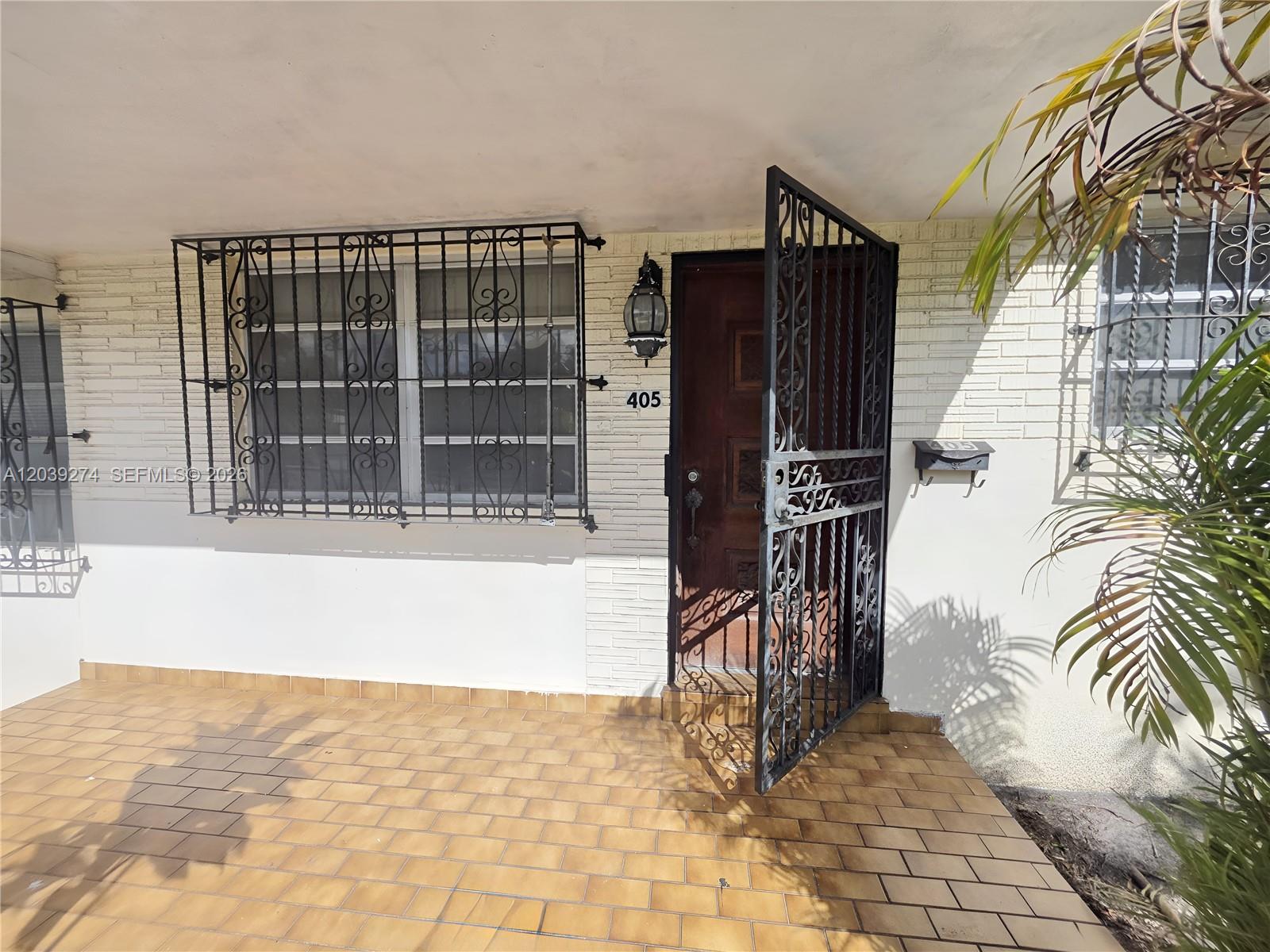 A front porch features a tiled floor, a wooden door with a decorative metal security gate — 405 SE 4th Ave, Hialeah FL 33010, HIALEAH, FL