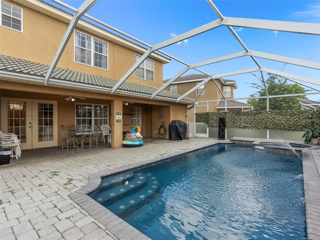 A screened-in patio features a swimming pool with steps and a paved deck area — 426 VISTA LOOP, DAVENPORT, FL
