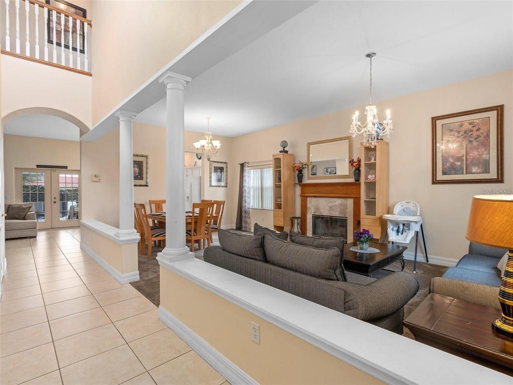 A living room with a fireplace, dining area, and tiled entryway with white columns — 426 VISTA LOOP, DAVENPORT, FL