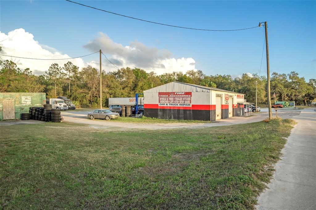 A commercial auto repair shop with a red and black exterior sits on a gravel lot — 3109 S FLORIDA AVENUE, INVERNESS, FL
