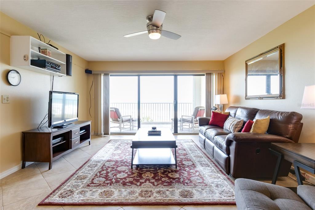 A living room features a leather sofa, a television on a stand, and a balcony view — 555 HARRISON AVENUE UNIT 402, CAPE CANAVERAL, FL