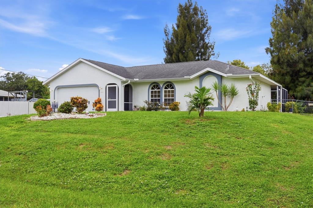 A single-story white house with a garage and a large grassy front yard — 650 CHEVY CHASE STREET, PORT CHARLOTTE, FL