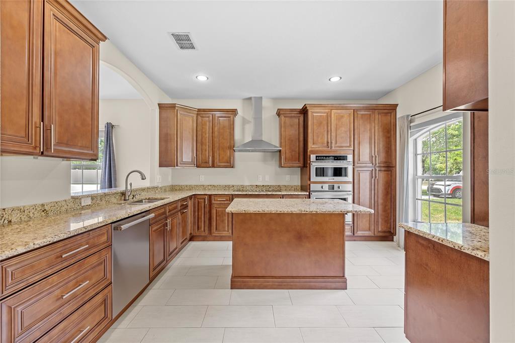 A kitchen features wood cabinets, granite countertops, stainless steel appliances, and light-colored tile flooring — 1557 BLACKWOOD AVENUE, GOTHA, FL