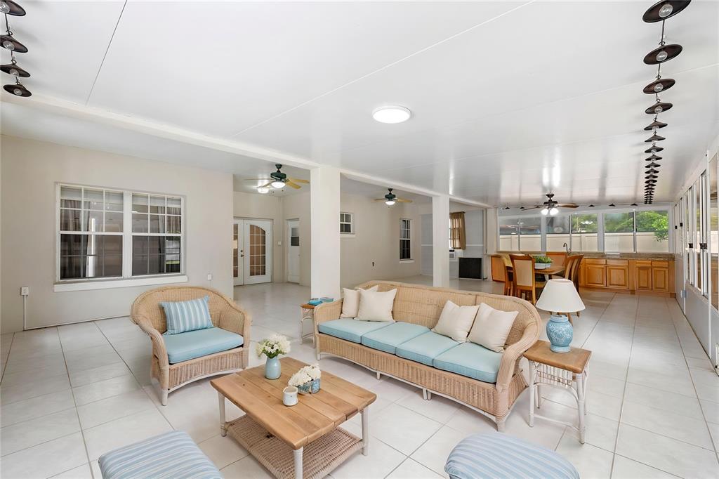 A spacious, tiled sunroom features wicker furniture, a dining area, and multiple ceiling fans — 1557 BLACKWOOD AVENUE, GOTHA, FL