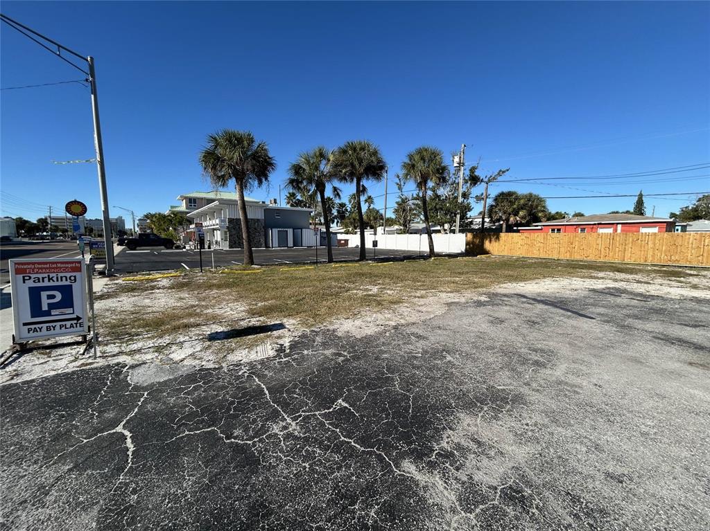 A paved parking lot features a "Pay by Plate" sign and several palm trees — 14225 GULF BOULEVARD, MADEIRA BEACH, FL