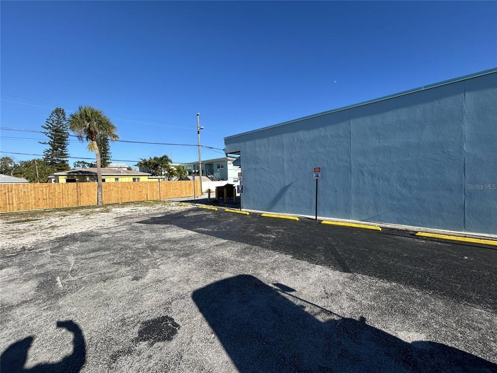 A paved parking area sits beside a light blue building with yellow parking stops — 14225 GULF BOULEVARD, MADEIRA BEACH, FL