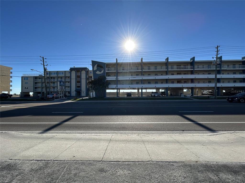 A multi-story apartment building with a parking level sits behind a road and sidewalk — 14225 GULF BOULEVARD, MADEIRA BEACH, FL