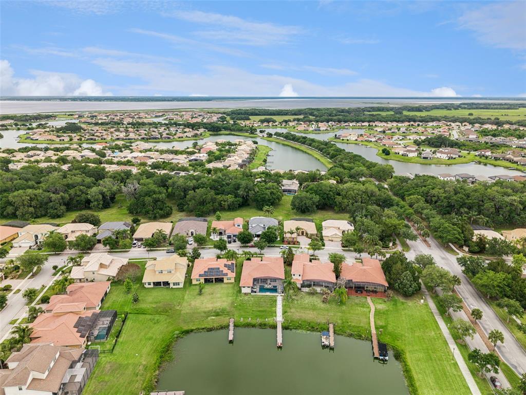 An aerial view shows a suburban neighborhood with houses bordering a small lake and wetlands — 3704 EAGLE ISLE CIRCLE, KISSIMMEE, FL