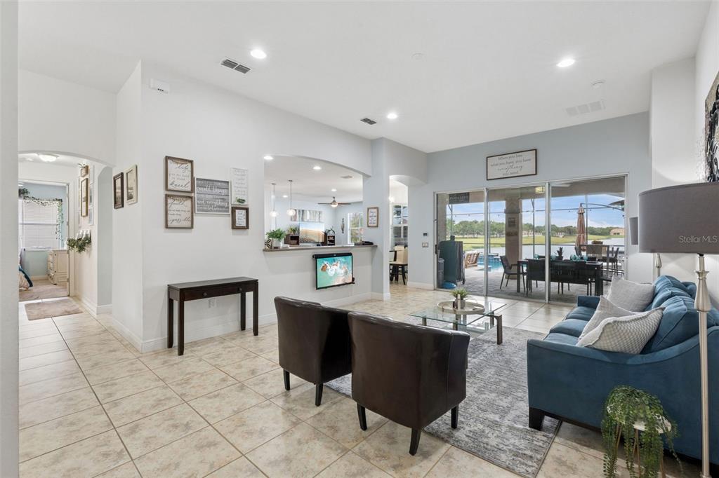 A living room with tile floors, a blue sofa, and a view of a pool — 3704 EAGLE ISLE CIRCLE, KISSIMMEE, FL