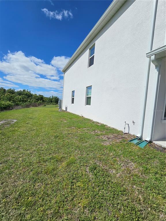 The side exterior of a white stucco house features two windows and a downspout — 3054 CHANTILLY DRIVE, DAVENPORT, FL