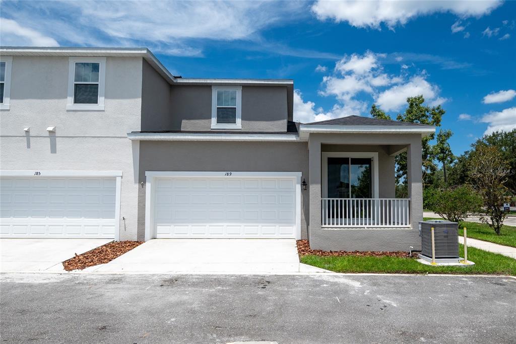 A two-story townhouse exterior features a white garage door, a covered porch, and gray siding — 189 BEAR SPRINGS DRIVE, WINTER SPRINGS, FL