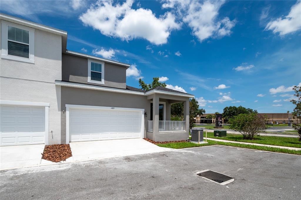 A two-story townhouse with a white garage door, gray siding, and a small covered porch — 189 BEAR SPRINGS DRIVE, WINTER SPRINGS, FL