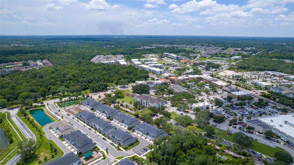 An aerial view shows a suburban neighborhood with townhomes, a pond, and nearby commercial buildings — 189 BEAR SPRINGS DRIVE, WINTER SPRINGS, FL