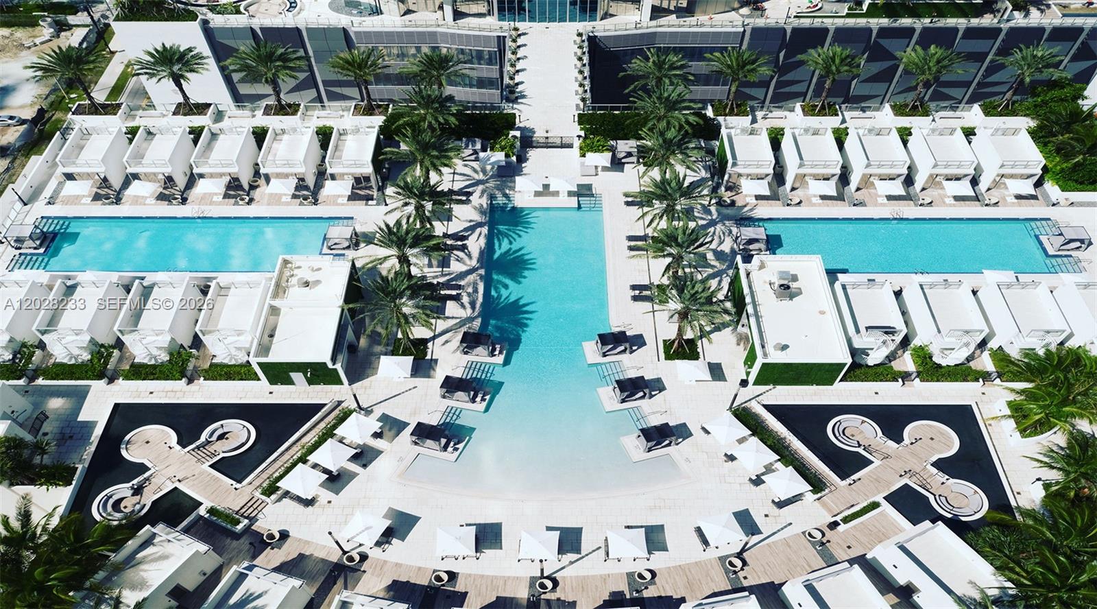 An aerial view shows a resort-style swimming pool surrounded by cabanas and palm trees — 851 NE 1st Ave # 4107, Miami FL 33132, MIAMI, FL