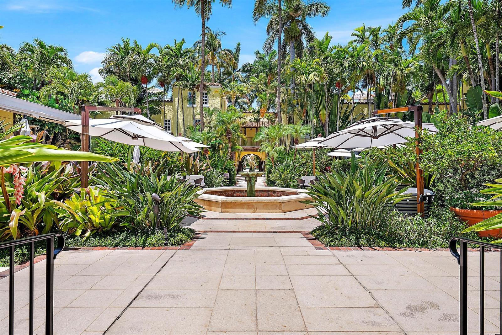A stone patio leads to a central fountain surrounded by lush tropical landscaping and umbrellas — 301 Australian Avenue # 301, Palm Beach FL 33480, PALM BEACH, FL