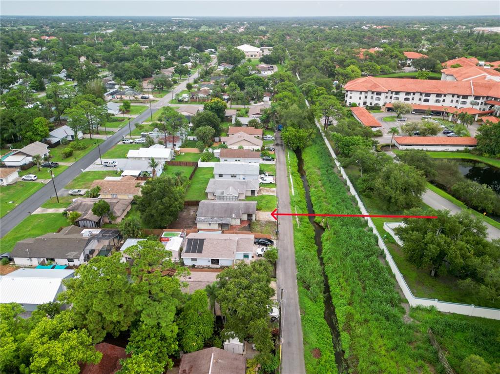 An aerial view shows a residential street with houses bordering a narrow canal and vegetation — 2227 BENSON STREET, SARASOTA, FL